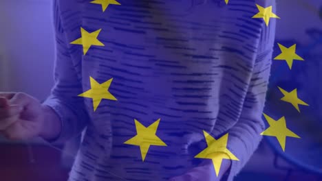 EU-Flagge-Weht-Gegen-Frau,-Die-Gesichtsmaske-Näht