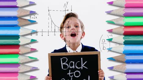 Mathematische-Gleichungen-Und-Buntstifte-Vor-Dem-Jungen,-Der-Eine-Tafel-Mit-Text-Zurück-Zur-Schule-Hält