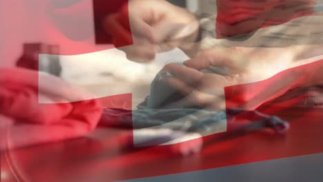 Swiss-flag-waving-against-mid-section-of-woman-sewing-face-mask