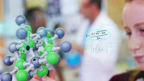 Mathematical-equations-floating-against-girl-holding-chemical-structure-model-in-laboratory