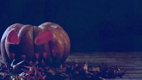 Scary-pumpkin-and-leaves-on-wooden-surface-against-flickering-background