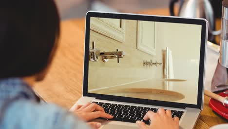 Woman-using-laptop-with-modern-bathroom-interiors-displayed-on-screen