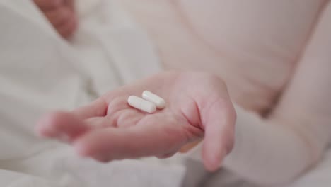 Close-up-of-woman-holding-pills-in-her-hand