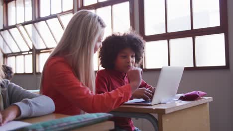 Female-teacher-and-boy-using-laptop-in-class-at-school
