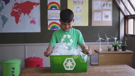 Niño-Sosteniendo-Un-Contenedor-De-Reciclaje-En-La-Clase-De-La-Escuela