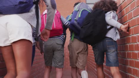 Rear-view-of-group-of-kids-with-backpacks-running