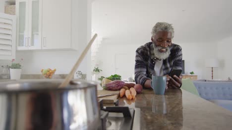 Senior-man-using-smartphone-in-the-kitchen