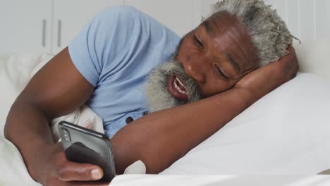 Älterer-Mann,-Der-Zu-Hause-Im-Bett-Einen-Videochat-Auf-Seinem-Smartphone-Führt