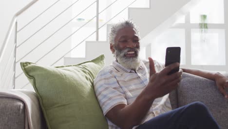 Älterer-Mann,-Der-Zu-Hause-Einen-Video-Chat-Auf-Seinem-Smartphone-Führt