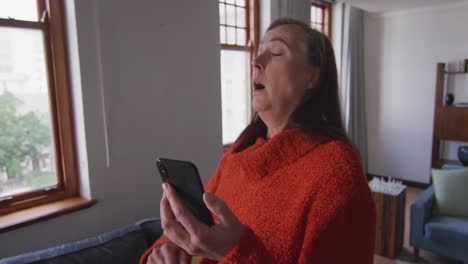 Kranke-Frau-Niest,-Während-Sie-Zu-Hause-Ihr-Smartphone-Benutzt