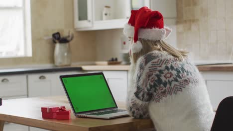 Woman-wearing-Santa-hat-having-a-video-chat-on-her-laptop-at-home