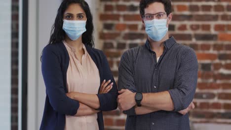 Portrait-of-man-and-woman-wearing-face-masks-in-office