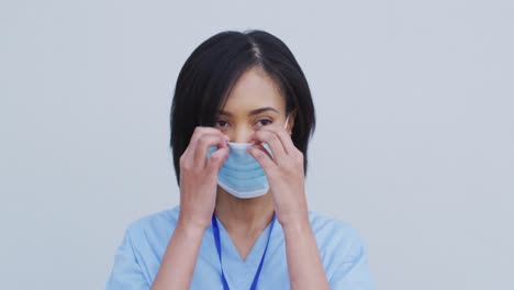 Portrait-of-Female-health-worker-wearing-face-mask-against-white-background