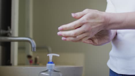 Mid-section-of-woman-sanitizing-her-hands-at-home