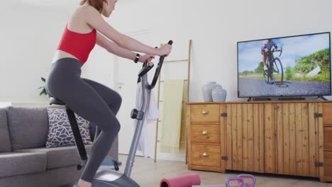 Frau-Trainiert-Auf-Einem-Stationären-Fahrrad,-Während-Sie-Zu-Hause-Fernsieht
