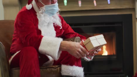 Weihnachtsmann-Trägt-Gesichtsmaske-Und-Schenkt-Geschenkbox