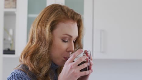 Woman-drinking-coffee-in-the-kitchen-at-home