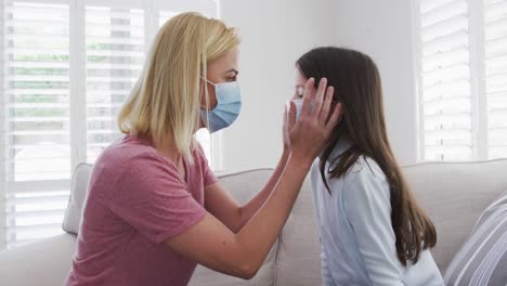 Mother-putting-face-mask-on-her-daughter-at-home