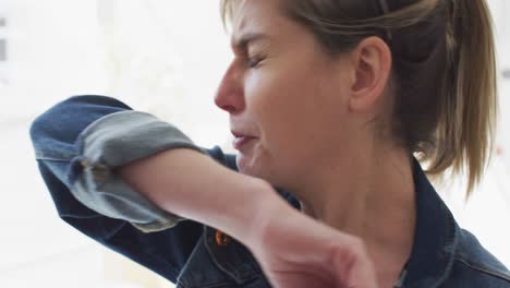 Woman-sneezing-on-her-elbow-at-office