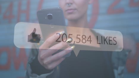 Speech-bubble-with-thumbs-up-icon-and-increasing-numbers-against-woman-using-smartphone