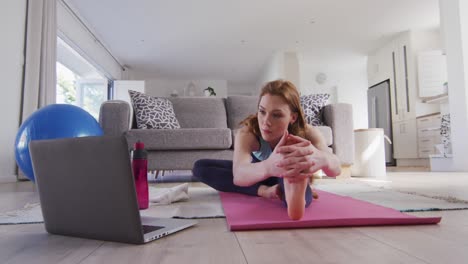 Mujer-Practicando-Yoga-Mientras-Mira-En-La-Computadora-Portátil-En-Casa
