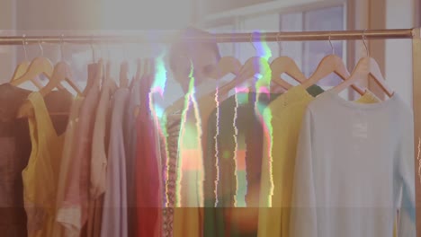 Digital-animation-of-sales-text-in-static-effect-against-woman-selecting-dresses-in-a-boutique