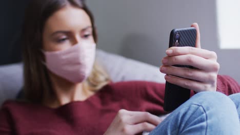 Woman-wearing-face-mask-wiping-her-smartphone-with-a-tissue