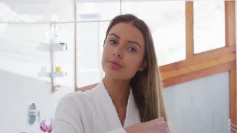 Portrait-of-woman-in-bathrobe-brushing-her-hair-in-bathroom