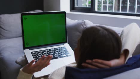 Woman-using-laptop-while-lying-on-couch-at-home