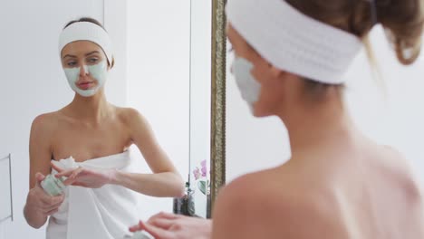 Frau-Trägt-Gesichtsmaske-Auf,-Während-Sie-Im-Badezimmer-In-Den-Spiegel-Schaut