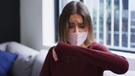 Woman-wearing-face-mask-sneezing-on-her-elbow