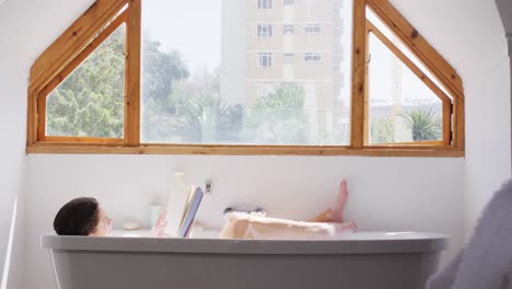 Woman-reading-a-book-while-relaxing-in-a-bathtub