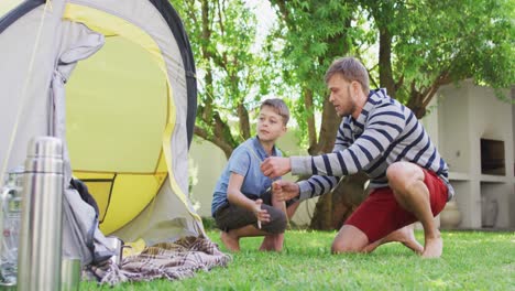 Caucasian-man-and-his-son-in-the-garden-putting-up-a-tent-talking-and-high-fiving
