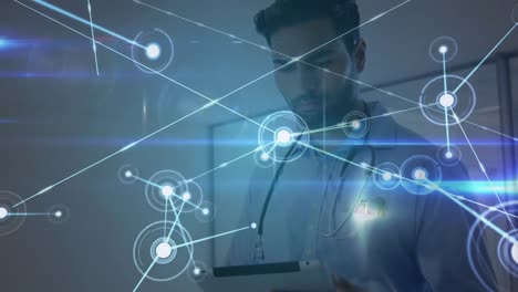 Network-of-connections-and-glowing-blue-light-trails-against-male-doctor-with-stethoscope-around-his