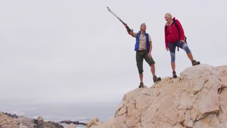 Senior-hiker-couple-with-backpack-and-trekking-poles-pointing