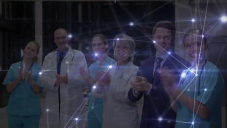 Network-of-connections-against-team-of-medical-professional-clapping-at-hospital