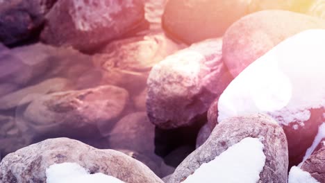 Animation-of-stones-in-water-during-winter-covered-in-snow-and-frost-with-light-spots