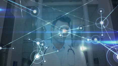 Network-of-connections-and-blue-glowing-light-trails-against-male-doctor-using-digital-tablet-at-hos