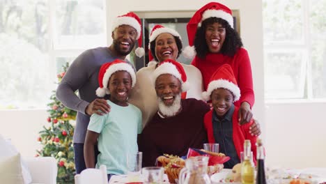 Porträt-Einer-Afroamerikanischen-Familie-Mit-Weihnachtsmützen,-Die-Zu-Hause-Zusammen-Lächelt