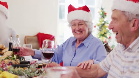 Caucasian-senior-couple-in-santa-hats-talking-and-smiling