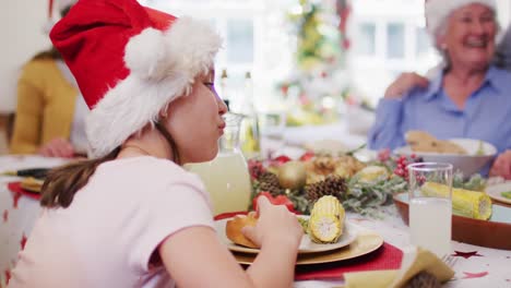 Kaukasische-Familie-In-Weihnachtsmützen-Genießt-Gemeinsam-Das-Mittagessen,-Während-Sie-Zu-Hause-Am-Esstisch-Sitzt