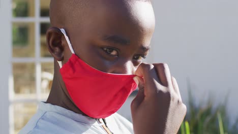 Portrait-of-african-american-boy-wearing-face-mask-outdoors-on-a-bright-sunny-day