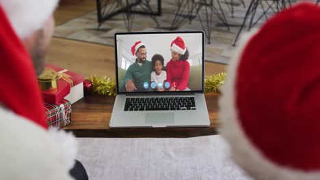 Caucasian-man-and-son-in-santa-hats-having-a-video-chat-at-christmas