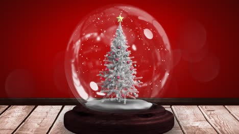 Animación-Del-árbol-De-Navidad-En-Globo-De-Nieve-Sobre-Superficie-De-Madera-Sobre-Fondo-Rojo