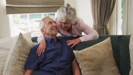 Senior-caucasian-couple-embracing-and-smiling-on-sofa-in-living-room-in-slow-motion