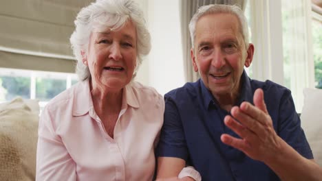 Portrait-of-senior-caucasian-couple-smiling-and-waving-to-camera