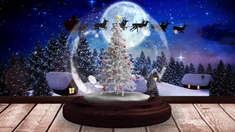 Digital-animation-of-shooting-stars-spinning-around-christmas-tree-in-snow-globe-on-wooden-surface