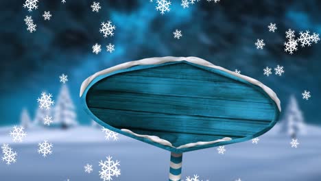 Digitale-Animation-Von-Schneeflocken,-Die-über-Einen-Blauen-Holzschildpfosten-In-Einer-Winterlandschaft-Gegen-Die-Nacht-Fallen