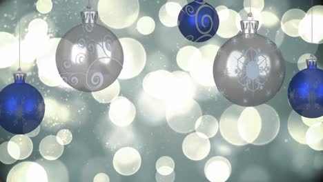 Animation-of-blue-and-silver-christmas-baubles-decoration-and-multiple-white-spots-of-light-on-grey-