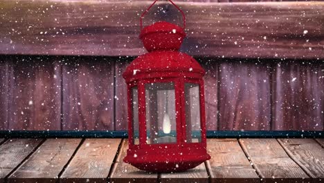 Digital-animation-of-snow-falling-over-christmas-lantern-on-wooden-surface